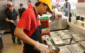 French Fry Heaven employee Dominic Abalos sprinkles some seasoning onto a batch of fries at the chain’s Tempe location. (Photo by Jason Axelrod/Cronkite News)