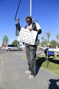 Wallace J. Brown Sr. waves his cane at honking cars passing by in support of a veterans rally at the Phoenix VA Medical Center on Monday, Nov. 9, 2015. He said he had hoped President Obama's visit back in March would have led to improvements in patient care. (Photo by April Morganroth/Cronkite News)