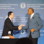 Randall Cunningham, new member of the College Football Hall of Fame, is greeted by ESPN's Joe Tessitore during the announcement news conference for the 2016 class. (Photo by Bill Slane/Cronkite News)