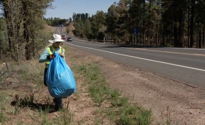 A volunteer from the Adopt a Highway program moves a garbage bag full of litter in Pinetop. (Photo courtesy of Arizona Department of Transportation)