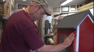 Don Krug works on the finishing touches of the Little Free Library he built and donated to the Southwest Human Development. (Photo by Lauren Michaels/Cronkite News)