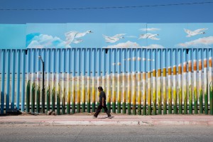 A man walks past the painted border fence in Agua Prieta, Mexico. Residents of Agua Prieta and Douglas say they feel there’s a good relationship between the two cities. (Photo by Courtney Pedroza/Special for Cronkite News)