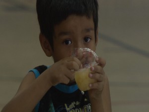 A little boy enjoys a fruit cup, part of his Kid’s Cafe meal.