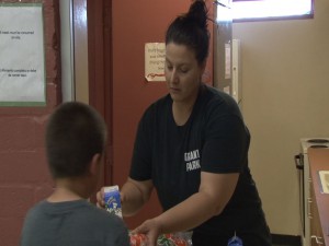 A Kid’s Cafe staffer hands out meals to the kids attending that day’s cafe service.