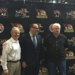 Tucson Mayor Jonathan Rothschild (left), Coyotes president Anthony LeBlanc (center) and Chairman of the board of Rio Nuevo Fletcher McCusker (right) pose in front of the new Tucson Roadrunners Logo. (Photo by Joe Steen/Cronkite News)