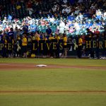 Doctors and nurses from Phoenix’s Children’s Hospital hold up cardboard signs that spell “Hope Lives Here," along the first baseline at the D-backs Go Gold for Childhood Cancer Awareness Game. (Photo by Giselle Cancio/Cronkite News)