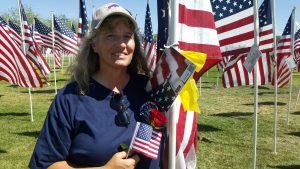 Phoenix mail carrier Angela DiMaria places roses on the flagpoles of firefighters who died during the 9/11 terrorism attacks. She visits the Healing Field in Tempe every year. (Photo by Michelle Chance/Cronkite News)