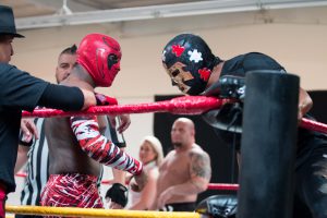 The masked luchadores Red Miracle, left, and Rompecabezas speak before a match. (Photo by Christopher West/Cronkite News)