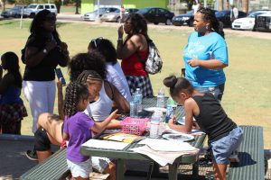 Children entertain themselves with coloring books at the National Day of Nonviolence, hosted by One Phoenix at Hermoso Park in Phoenix. (Photo by Cassie Ronda/Cronkite News)
