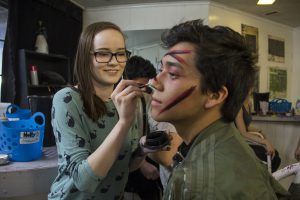 Holly Nesselrode applies makeup to John Villa to prepare for a night of scaring people in a haunted corn maze at Fear Farm in the West Valley. (Photo by Ally Carr/Cronkite News)