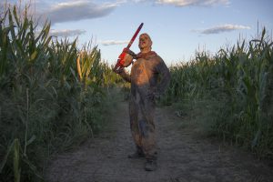 Chicken Lips, a monster that frightens guests at Fear Farm, stands with a chain saw in a corn maze. (Photo by Ally Carr/Cronkite News)