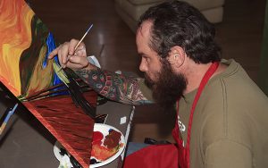U.S. Army veteran Ricardo Pereyda, 34, paints his version of Edvard Munch’s “The Scream” at the “Buds & Brushes” painting class at the 420 Social Club in Tucson, Ariz., on Saturday, Oct. 29. (Photo by Brian Fore/Cronkite News)