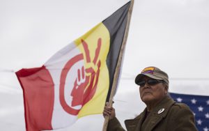 David Garcia stands holding the flag of the American Indian Movement during a gathering of social activists in Tucson, Arizona, on the day of President Donald Trump’s inauguration.  (Photo by Johanna Huckeba/Cronkite News)