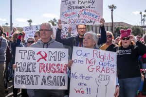 A family shows signs showcasing their views at a Phoenix march in support of the Women’s March on Washington. (Photo by Saeed Alshamisi/Cronkite News)