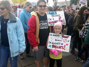 Gilbert father Casey Knapp, 38, stands with his 7-year-old daughter, who made her own sign. (Photo by Saundra Wilson/Cronkite News)