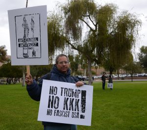Phoenix resident Randy Dinin, 53, stands in front of the Arizona State Capitol on Friday, Jan. 20, 2017, in protest of President Donald Trump’s inauguration. Dinin’s signs read “NO TRUMP NO KKK NO FASCIST USA!” and “ANTI-COLONIAL ANTI-FASCIST RESISTANCE.” (Photo by Ryan Santistevan/Cronkite News)