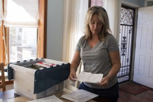 Tucson resident Susan Romeo keeps a crate full of bills from treatment centers to fight her son’s addiction. (Photo by Kristiana Faddoul/Cronkite News)