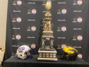 The Fiesta Bowl trophy sits between TCU and Michigan helmets at the Fiesta Bowl media day Thursday in Scottsdale. The trophy winner will be determined Saturday at State Farm Stadium in Glendale. (Photo by Nicholas Hodell/Cronkite News)